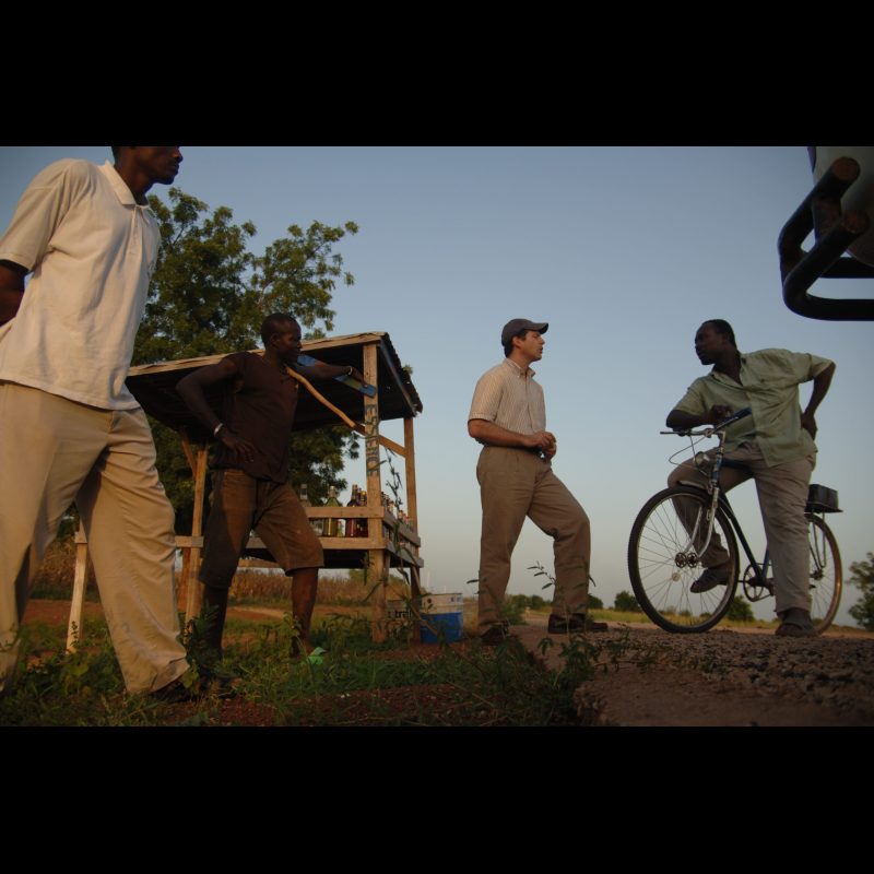 SOUMAGOU, Burkina Faso Jay Shafto (wearing the Boston Red Sox hat) stands with Paul Sow (in a white polo shirt), Antoine Tarnagda (in a brown shirt), and Zongo Tarnagda (on the bicycle) in the town of Soumagou. Antoine and Zongo are members of the Bissa tribe, while Paul is part of the Fulani tribe, reflecting the regions rich cultural diversity.
