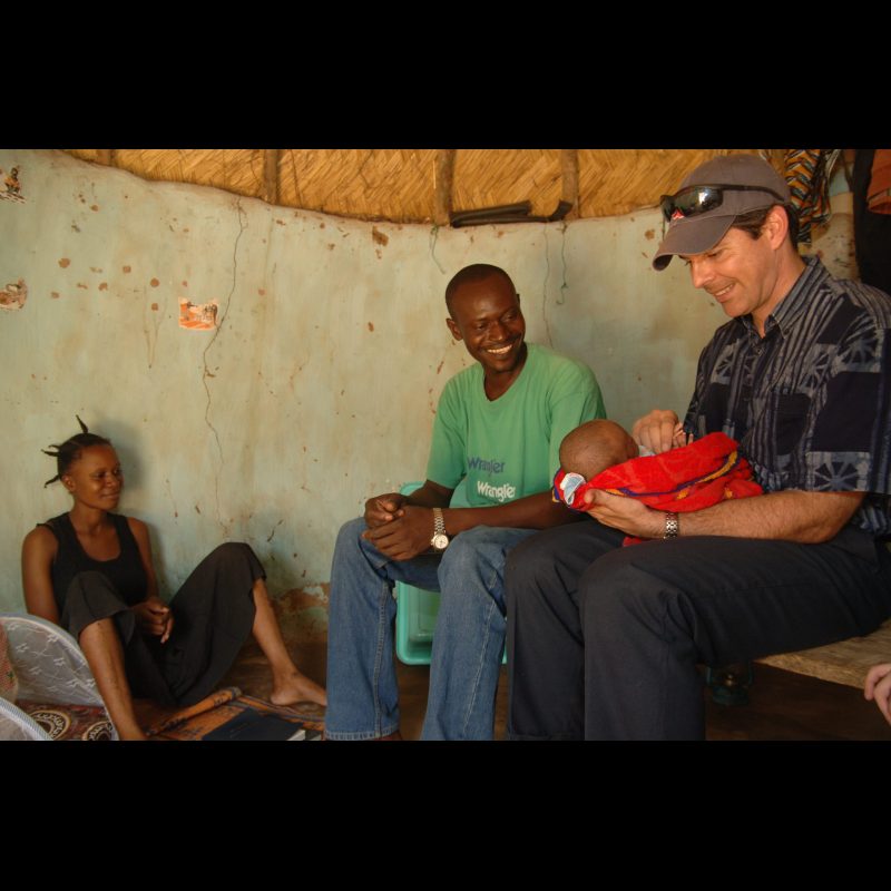 GARANGO, Burkina Faso — Awa and Cesare Bambaro, a male lay leader, sit with their daughter Rebekah and Jay Shafto inside a traditional hut in Garango. The visit reflects the strong relationships being built within the local faith community.