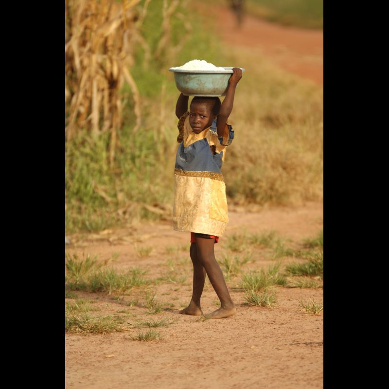 KONADOUGA, Burkina Faso A young girl carries a load on her head as she gazes curiously at visitorsbelieved to be the first white people she has seenin the village of Konadouga. Encounters like this highlight the remote nature of many Senara communities in Burkina Faso.