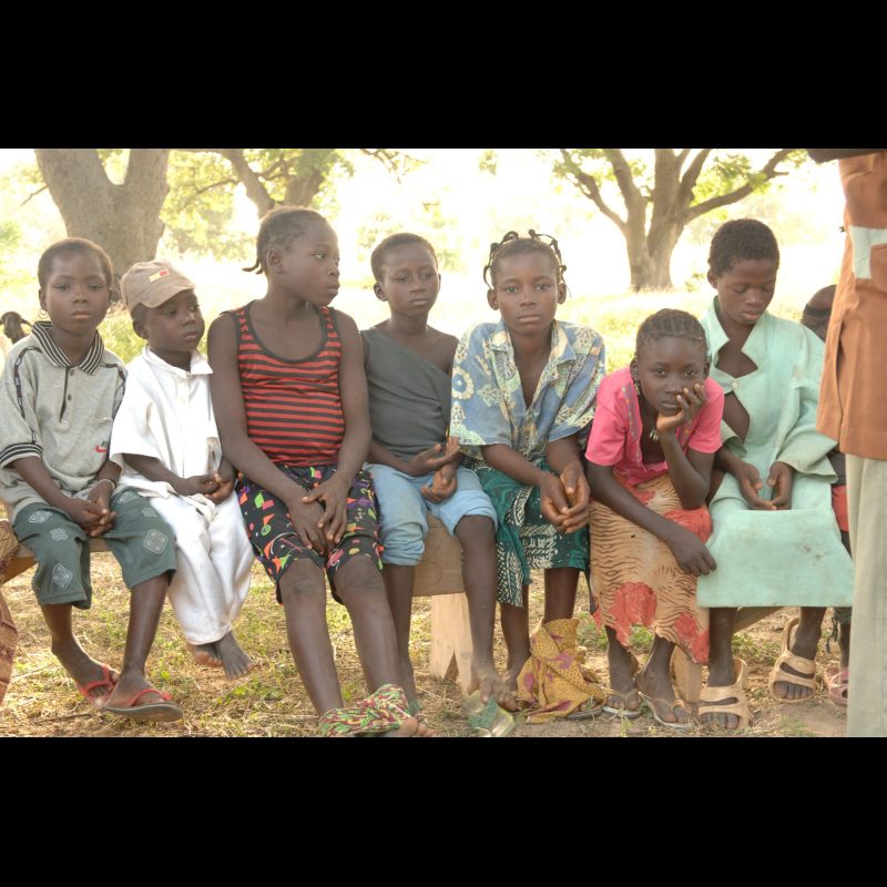 VILI VILLAGE, Burkina Faso — Children sit on a bench during a "Storying Point" gathering in Vili Village, just outside Koudougou, Burkina Faso. The group, started by Clarence and Lynn Lance, is led by Pastor Emanuel Yameogo and focuses on sharing Bible stories with the village's youngest members.