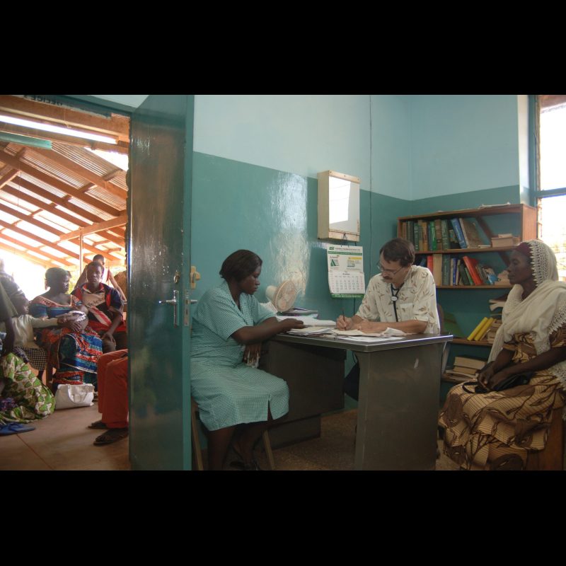 NALERIGU, Ghana Clinic attendant Ester Betnam assists Dr. George Faile, a general practitioner, as he sees patients at the Baptist Medical Centre in Nalerigu, Ghana. Outside his door, a long line of patients waits to be seen by him that day, reflecting the high demand for care.
