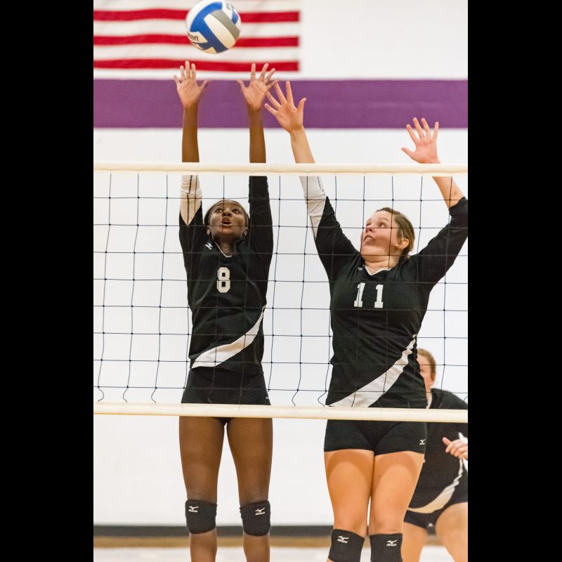 DECATUR, Ga. — Agnes Scott College women’s volleyball players jump to block a shot during game action. Competing in NCAA Division III, the team displays skill and teamwork as they defend the net with intensity.