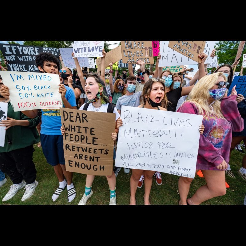 Libby Seger leads the group in chanting. She is holding the "Dear White People .." sign. The protesters are all laying down just like George Floyd did when he lost his life to a cop on his neck. Gwendolyn Dukes, Richard Bonito and their friends organized a peaceful protest on behalf of George Floyd at the corner or King Road and Hwy 92 in Roswell, Georgia on June 2, 2020. Dukes said, “Action speaks louder than words” as to why she and her friends wanted to get out and protest. Richard Bonito added, “We are not mad at the police, we are mad at the system.” They want to see changes for better policing, fixing systemic racism in our society and encouraging their friends to get out and vote. While Richard Bonito voted in the last presidential election most in the crowd are closer to Gwendolyn’s age and this will be their first election.